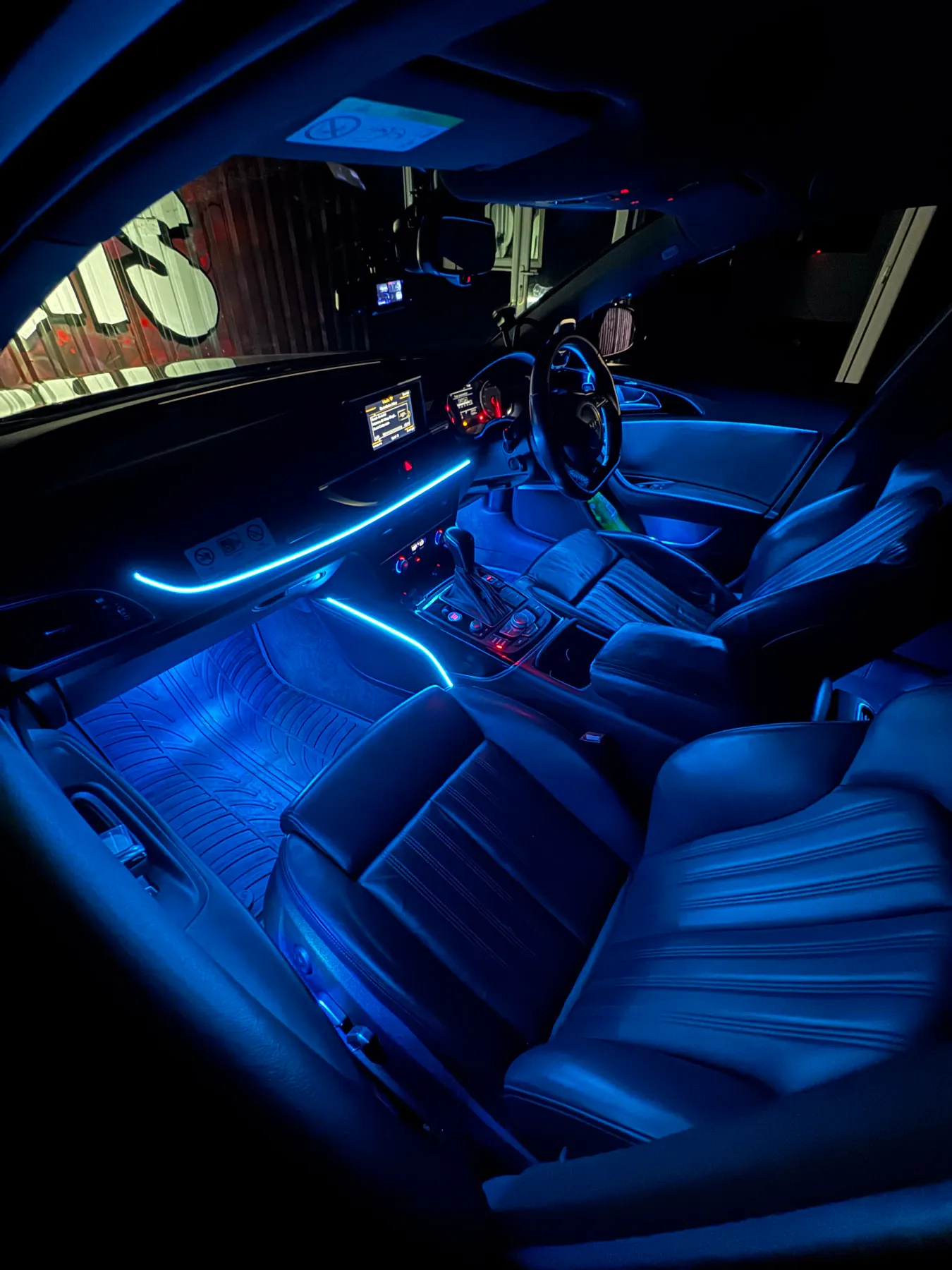 Audi interior with blue ambient lighting along the dashboard and footwells.