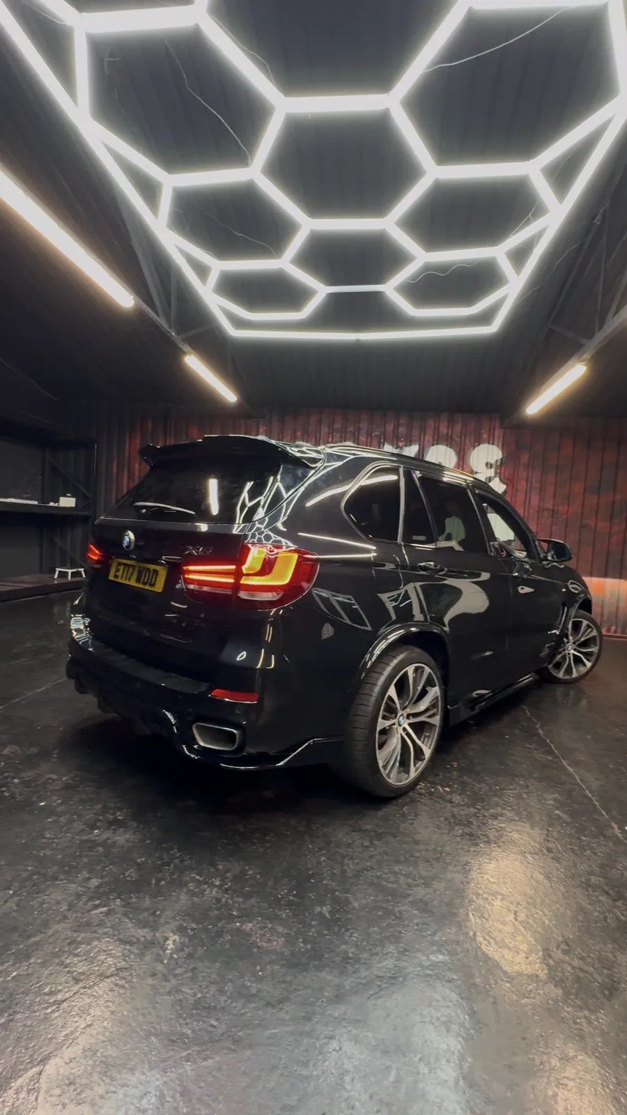 Rear of a styled black BMW X5 under the Secure Customs hexagon lighting.