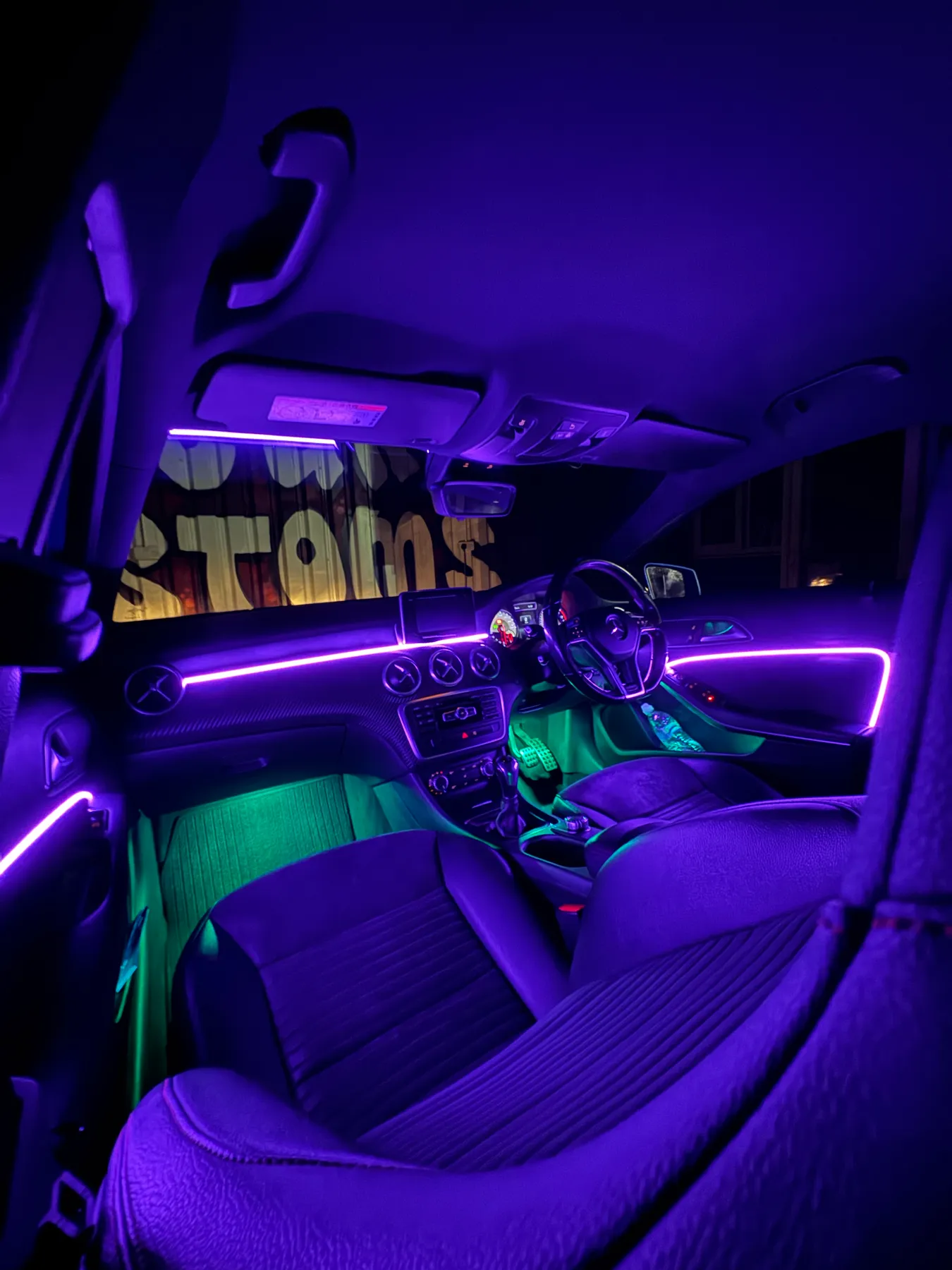 Mercedes interior with green footwell and purple dash ambient lighting fitted by Secure Customs.