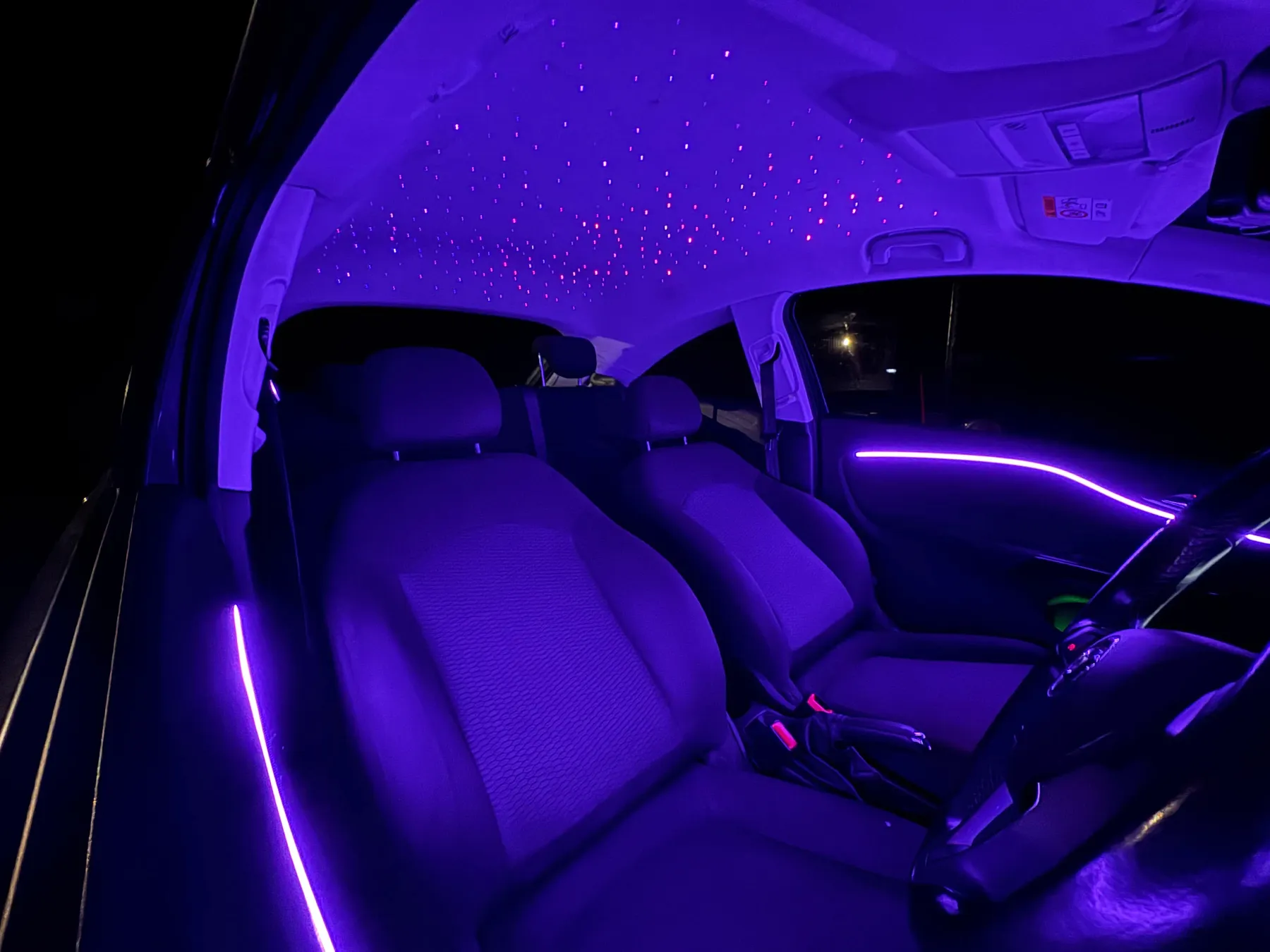 Car headliner fitted with a fibre-optic starlight roof and purple ambient lighting by Secure Customs.